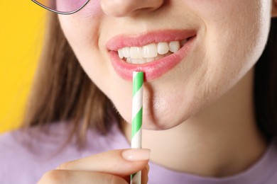 Photo of Woman with drinking straw on orange background, closeup