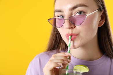 Photo of Woman drinking refreshing drink through straw on orange background, space for text
