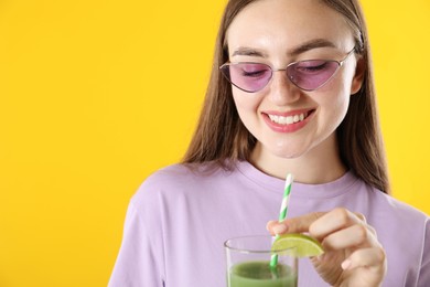 Photo of Woman with refreshing drink and straw on orange background, space for text