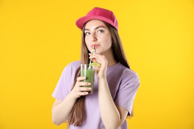 Photo of Woman drinking refreshing drink through straw on orange background