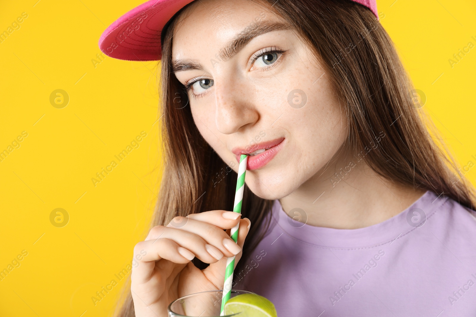 Photo of Woman drinking refreshing drink through straw on orange background, space for text