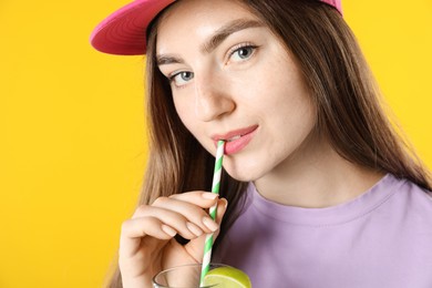 Photo of Woman drinking refreshing drink through straw on orange background, space for text