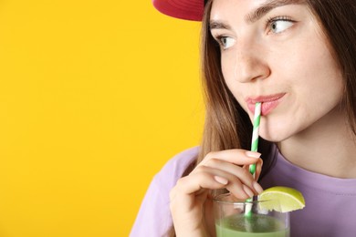 Photo of Woman drinking refreshing drink through straw on orange background, space for text