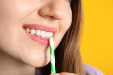 Photo of Woman drinking refreshing drink through straw on orange background, closeup