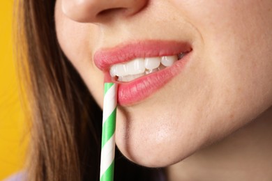 Photo of Woman drinking refreshing drink through straw on orange background, closeup