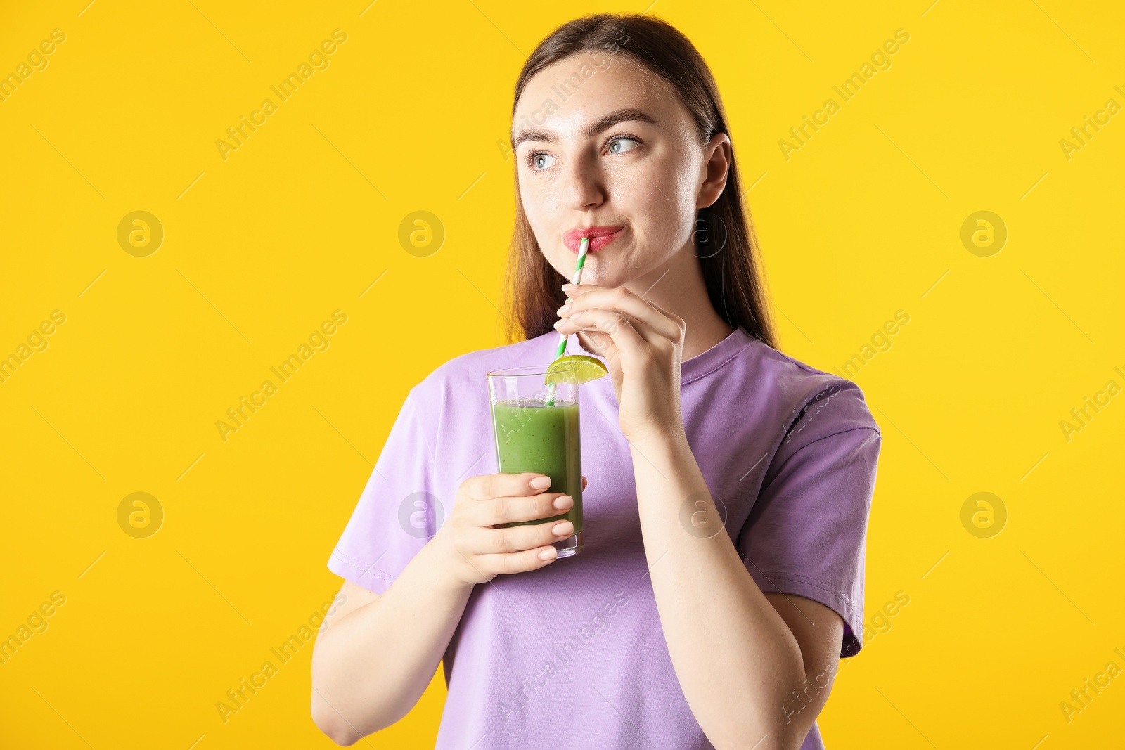 Photo of Woman drinking refreshing drink through straw on orange background