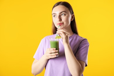 Photo of Woman drinking refreshing drink through straw on orange background