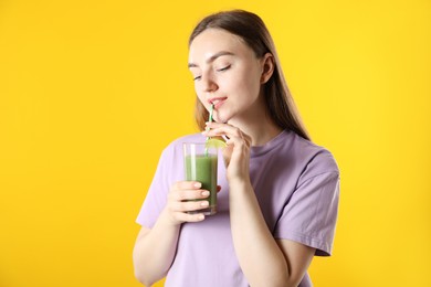 Photo of Woman drinking refreshing drink through straw on orange background