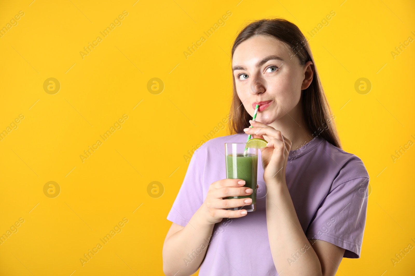 Photo of Woman drinking refreshing drink through straw on orange background, space for text