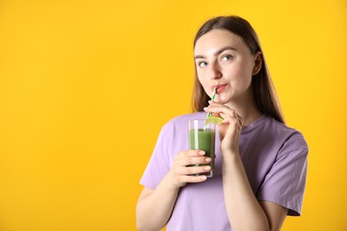 Photo of Woman drinking refreshing drink through straw on orange background, space for text