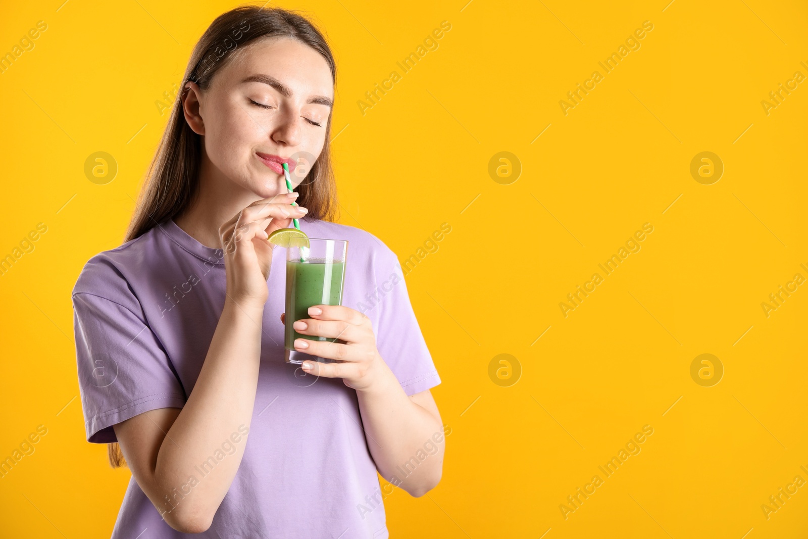 Photo of Woman drinking refreshing drink through straw on orange background, space for text
