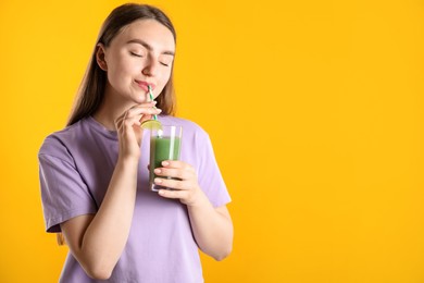 Photo of Woman drinking refreshing drink through straw on orange background, space for text