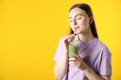 Photo of Woman drinking refreshing drink through straw on orange background, space for text