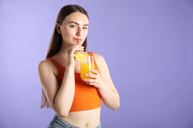 Photo of Woman drinking refreshing drink through straw on violet background, space for text