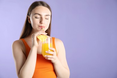 Photo of Woman drinking refreshing drink through straw on violet background, space for text