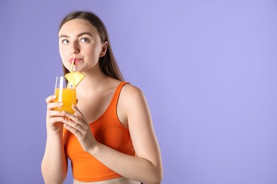 Photo of Woman drinking refreshing drink through straw on violet background, space for text
