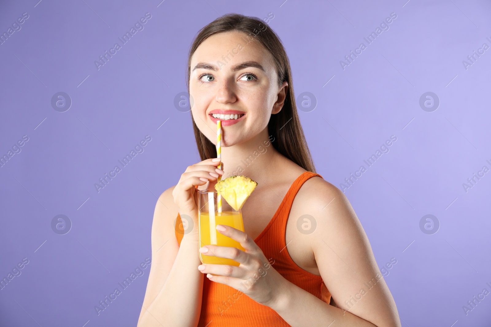 Photo of Woman drinking juice through straw on violet background