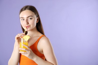 Photo of Woman drinking refreshing drink through straw on violet background, space for text