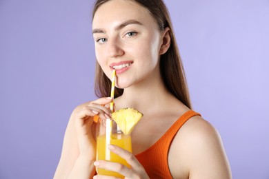 Photo of Woman drinking juice through straw on violet background