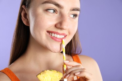 Photo of Woman drinking refreshing drink through straw on violet background