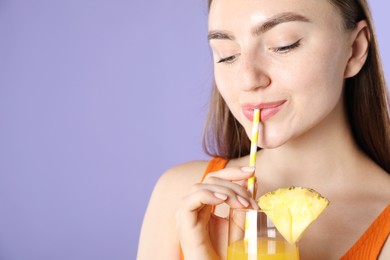 Photo of Woman drinking refreshing drink through straw on violet background, space for text