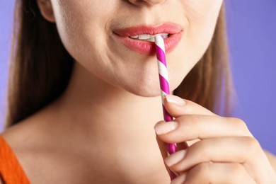 Photo of Woman with drinking straw on violet background, closeup