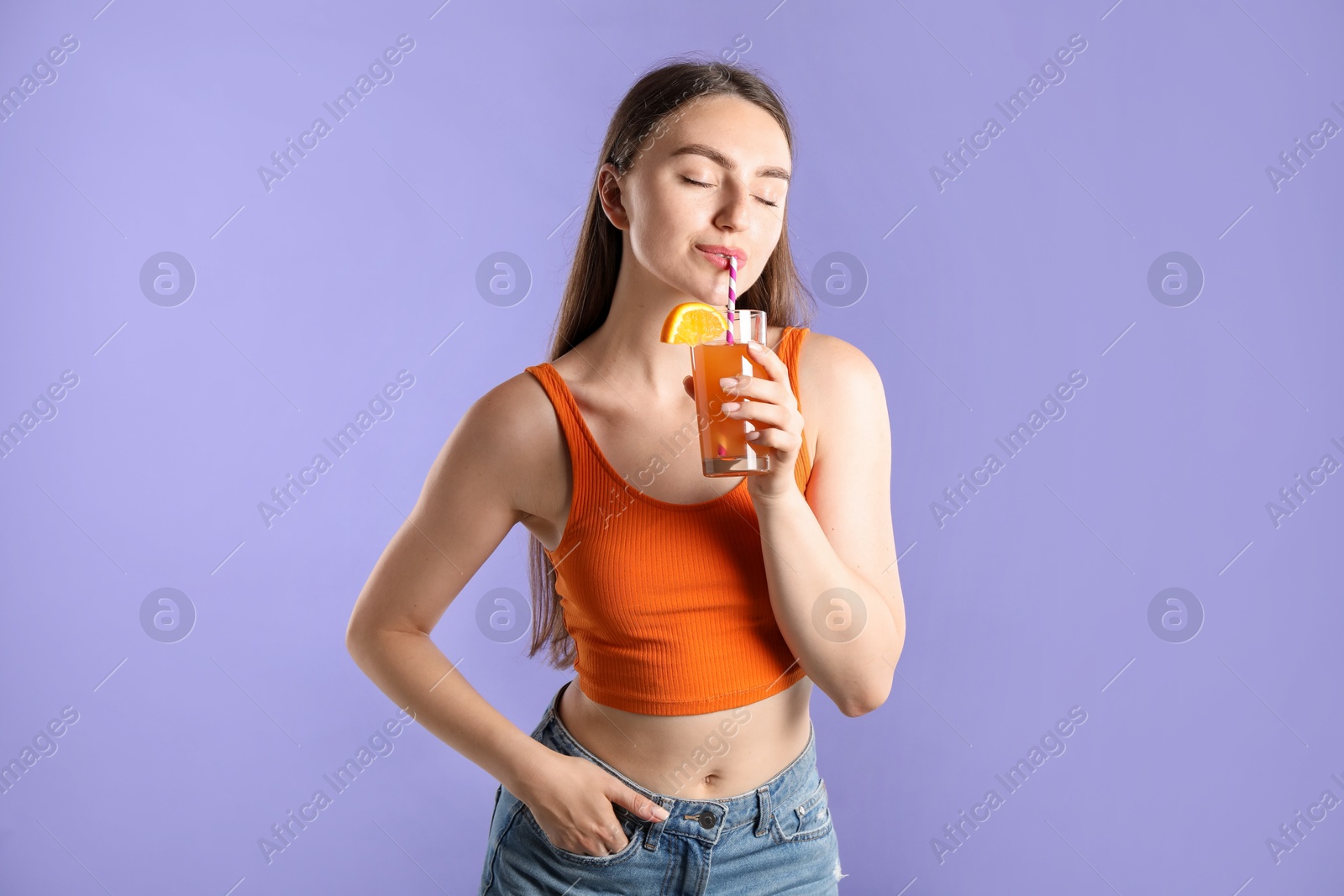 Photo of Woman drinking juice through straw on violet background