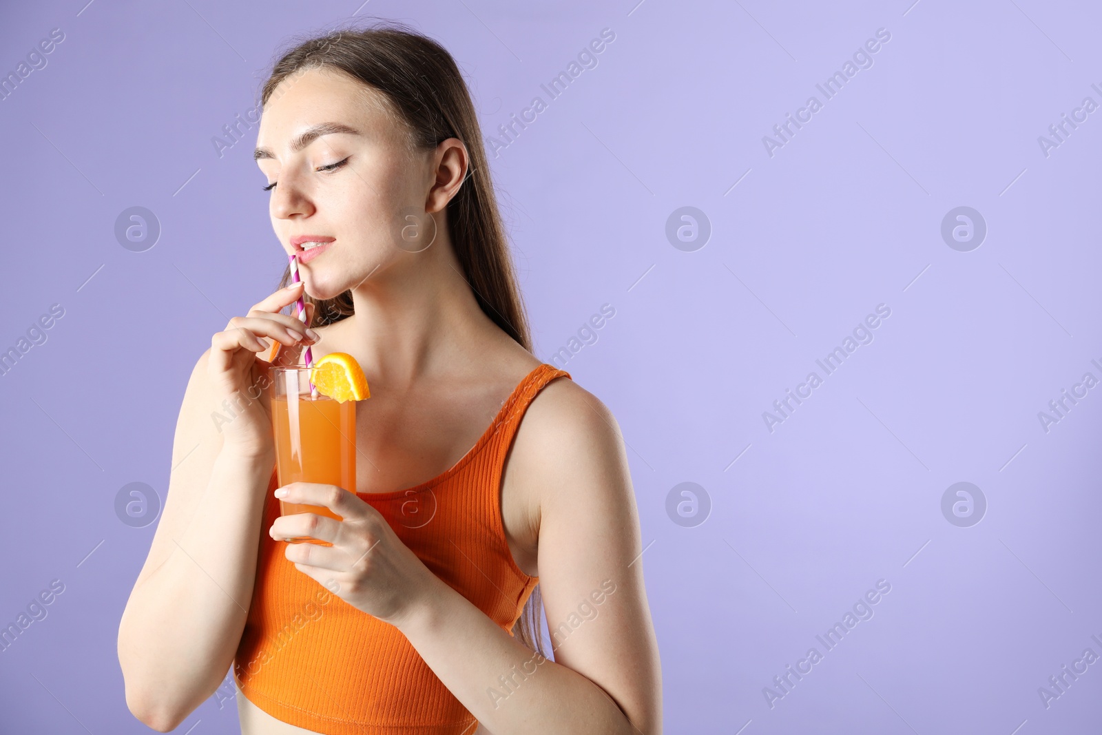 Photo of Woman drinking refreshing drink through straw on violet background, space for text