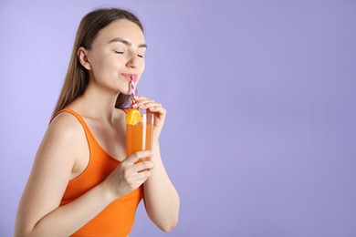 Photo of Woman drinking refreshing drink through straw on violet background, space for text