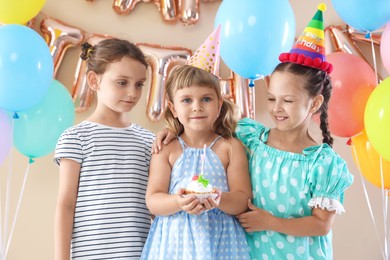 Photo of Birthday celebration. Kids with cupcake and different festive decor on beige background