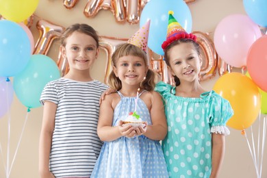 Photo of Birthday celebration. Kids with cupcake and different festive decor on beige background