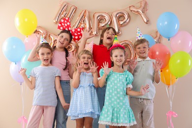 Photo of Birthday celebration. Happy kids with different festive decor on beige background