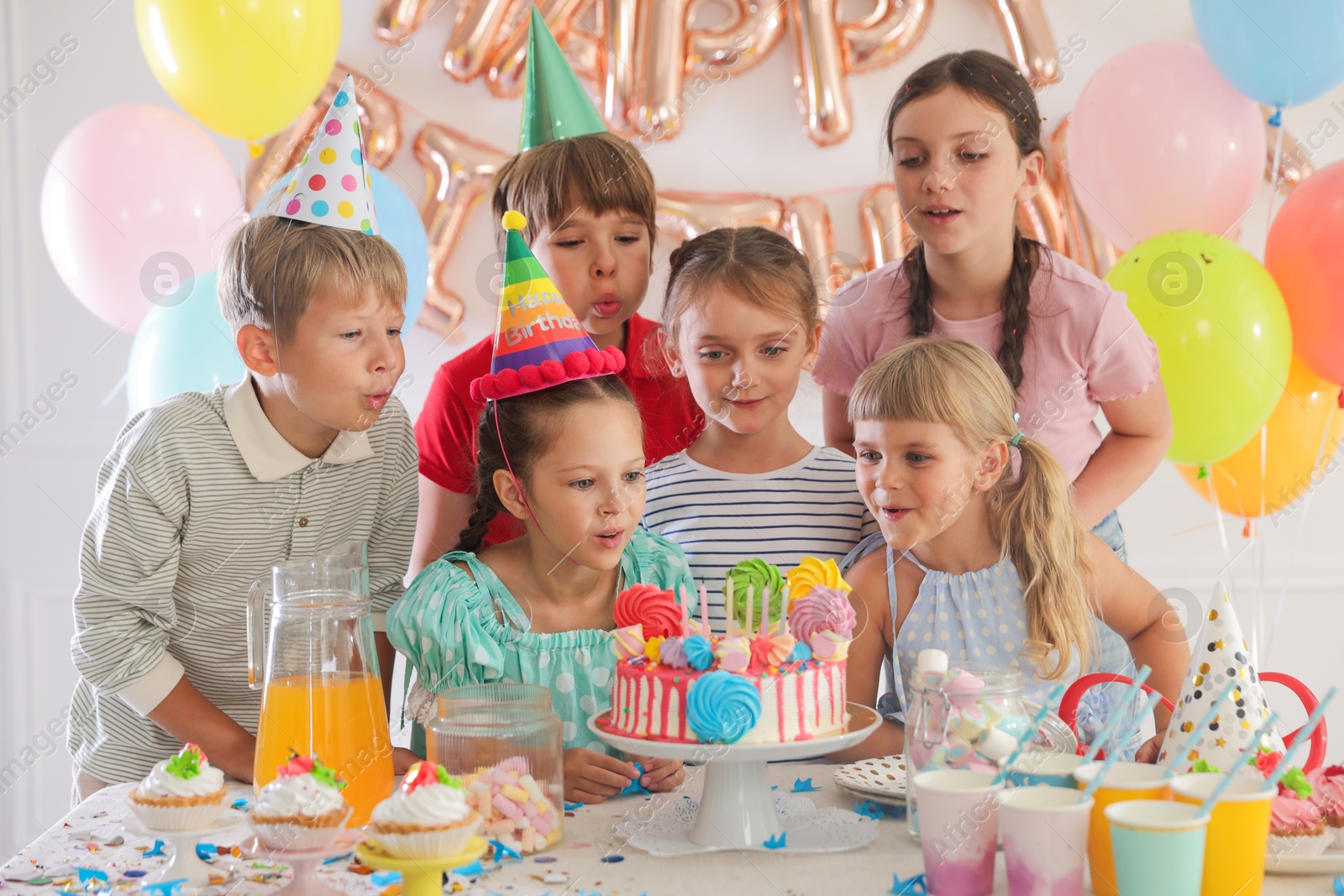 Birthday celebration. Kids at table with tasty cake and different treats in festive decorated room Photo of Birthday celebration. Kids at table with tasty cake and different treats in festive decorated room