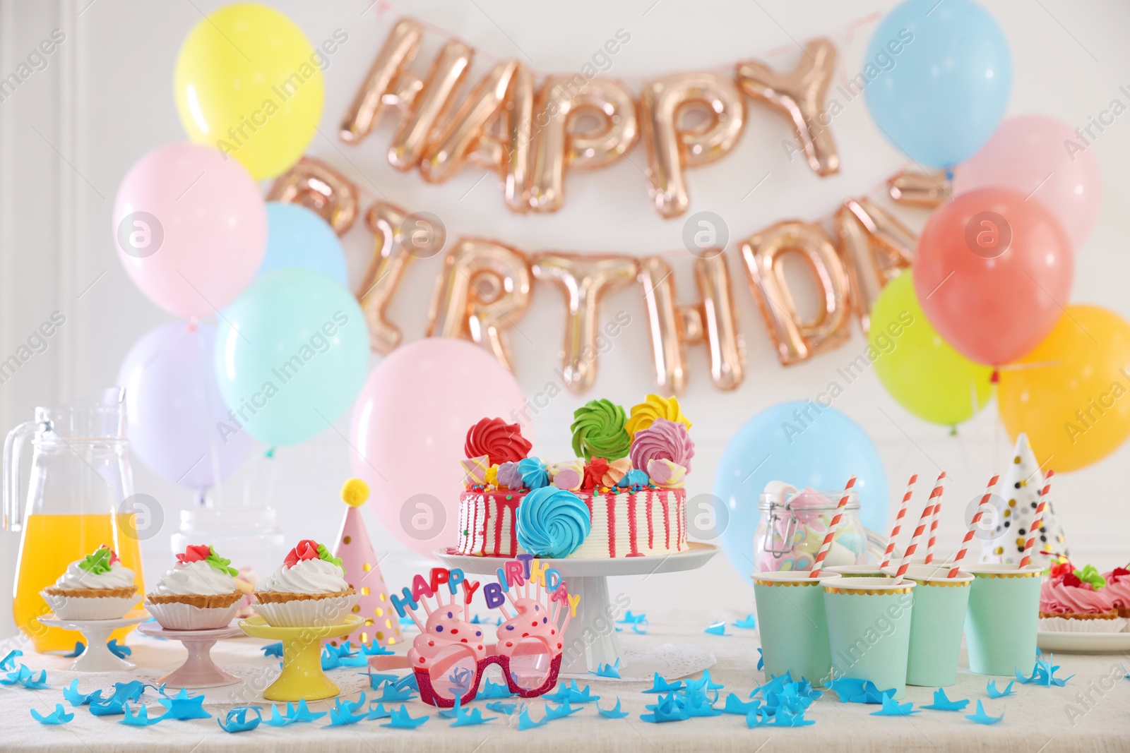 Birthday celebration. Tasty cake and different treats on table in festive decorated room Photo of Birthday celebration. Tasty cake and different treats on table in festive decorated room