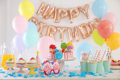 Photo of Birthday celebration. Tasty cake and different treats on table in festive decorated room
