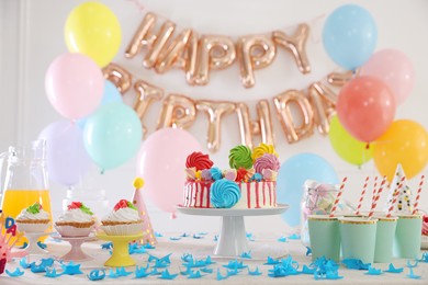 Photo of Birthday celebration. Tasty cake and different treats on table in festive decorated room