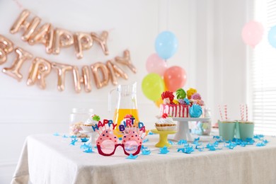 Photo of Birthday celebration. Tasty cake and different treats on table in festive decorated room