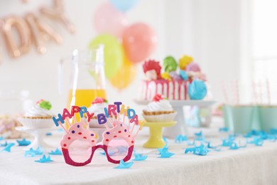 Photo of Birthday celebration. Different treats and decor on table indoors, closeup
