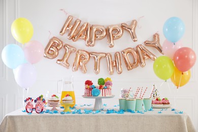 Photo of Birthday celebration. Tasty cake and different treats on table in festive decorated room