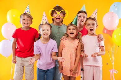 Photo of Birthday celebration. Happy kids and festive decor on orange background
