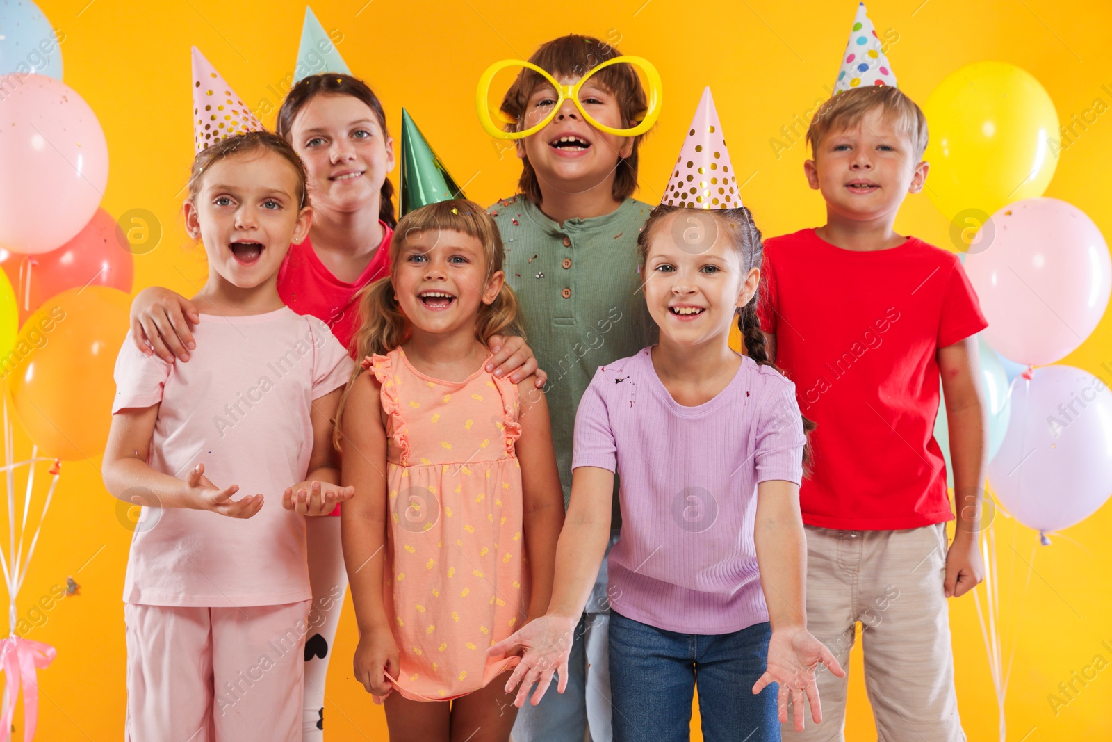Birthday celebration. Happy kids and festive decor on orange background Photo of Birthday celebration. Happy kids and festive decor on orange background