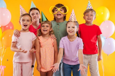 Photo of Birthday celebration. Happy kids and festive decor on orange background