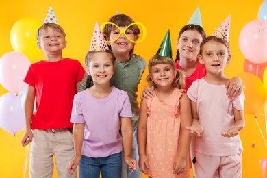 Photo of Birthday celebration. Happy kids and festive decor on orange background