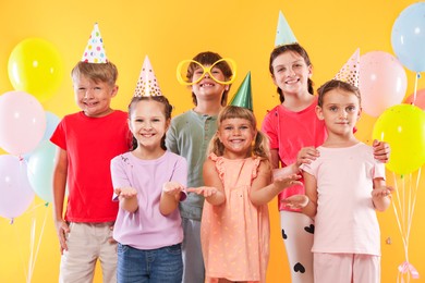 Photo of Birthday celebration. Happy kids and festive decor on orange background
