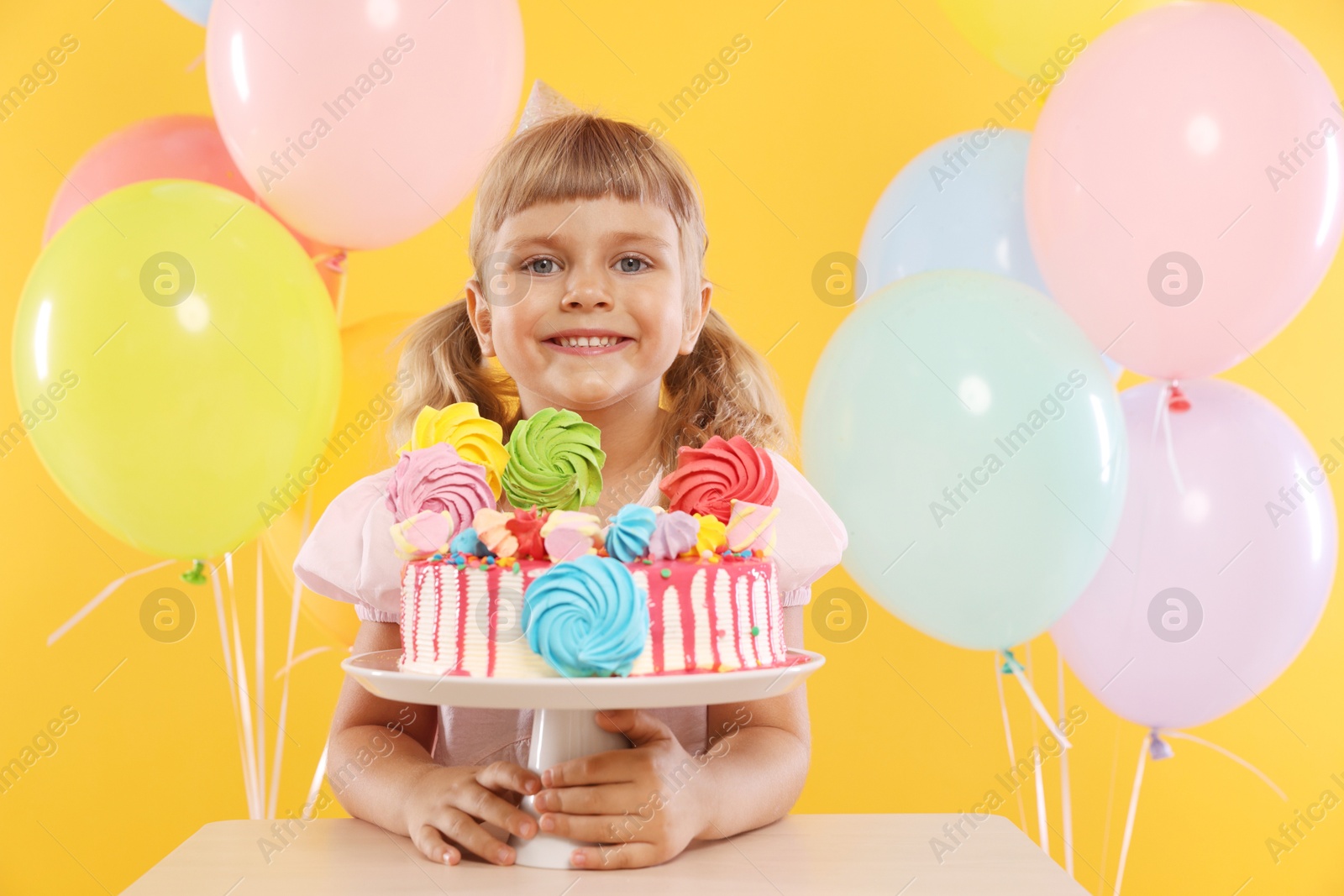 Birthday celebration. Cute little girl with tasty and balloons on orange background Photo of Birthday celebration. Cute little girl with tasty and balloons on orange background