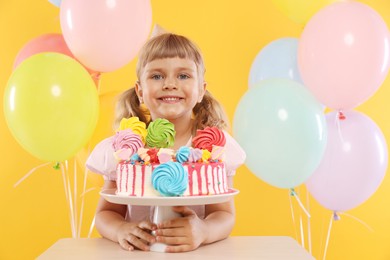 Photo of Birthday celebration. Cute little girl with tasty and balloons on orange background