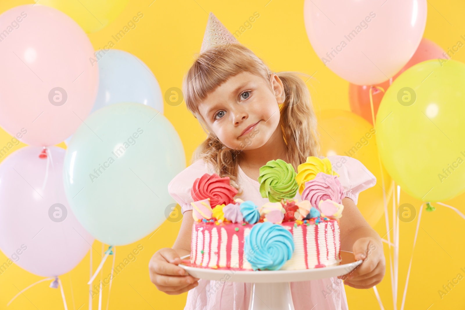 Birthday celebration. Cute little girl with tasty and balloons on orange background Photo of Birthday celebration. Cute little girl with tasty and balloons on orange background