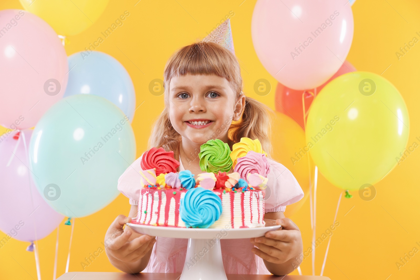Birthday celebration. Cute little girl with tasty and balloons on orange background Photo of Birthday celebration. Cute little girl with tasty and balloons on orange background