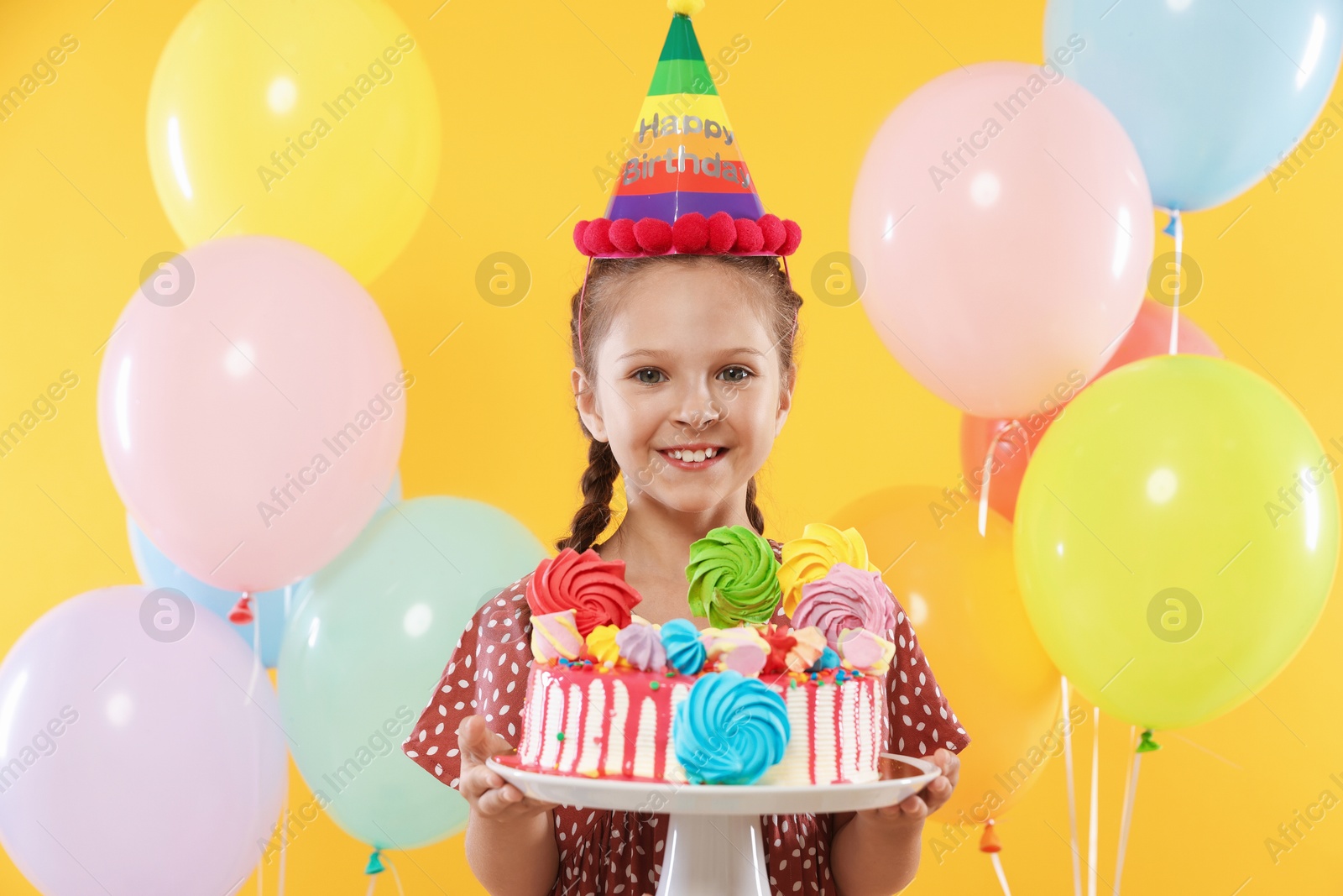 Birthday celebration. Cute little girl with tasty and balloons on orange background Photo of Birthday celebration. Cute little girl with tasty and balloons on orange background