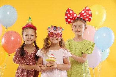 Photo of Birthday celebration. Kids with cupcake and balloons on orange background